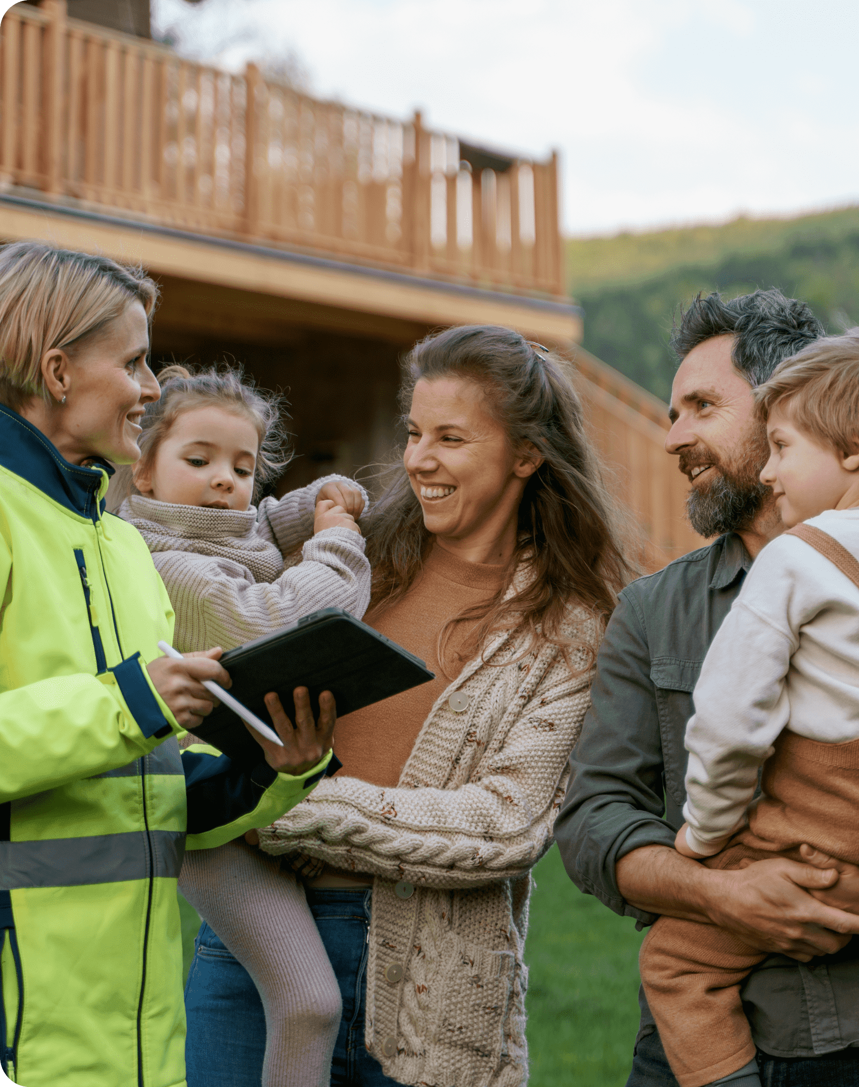 A smiling energy advisor in a high-visibility jacket shows a tablet to a family of four outside their home.