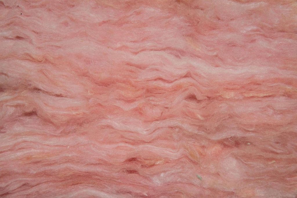 An extreme close up of one of the most popular types of home insulation: Fiberglass. It is cotton-like, dense, and pink.
