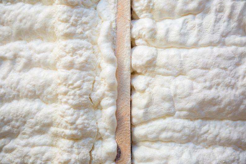 Close-up view of spray foam insulation applied to a surface, featuring a vertical seam in the middle and a textured, uneven appearance—demonstrating greenlink’s commitment to energy-efficient solutions.