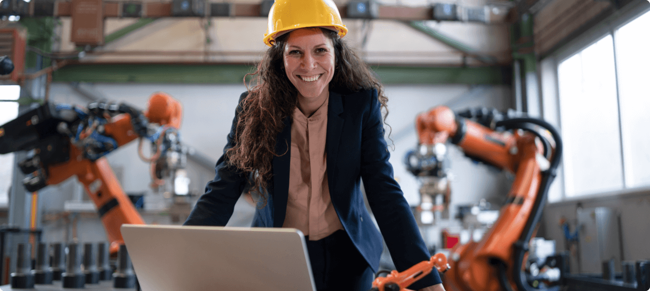Woman with Hardhat monitoring robotics with laptop